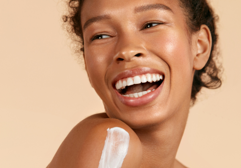 girl smiling and applying a moisturizer